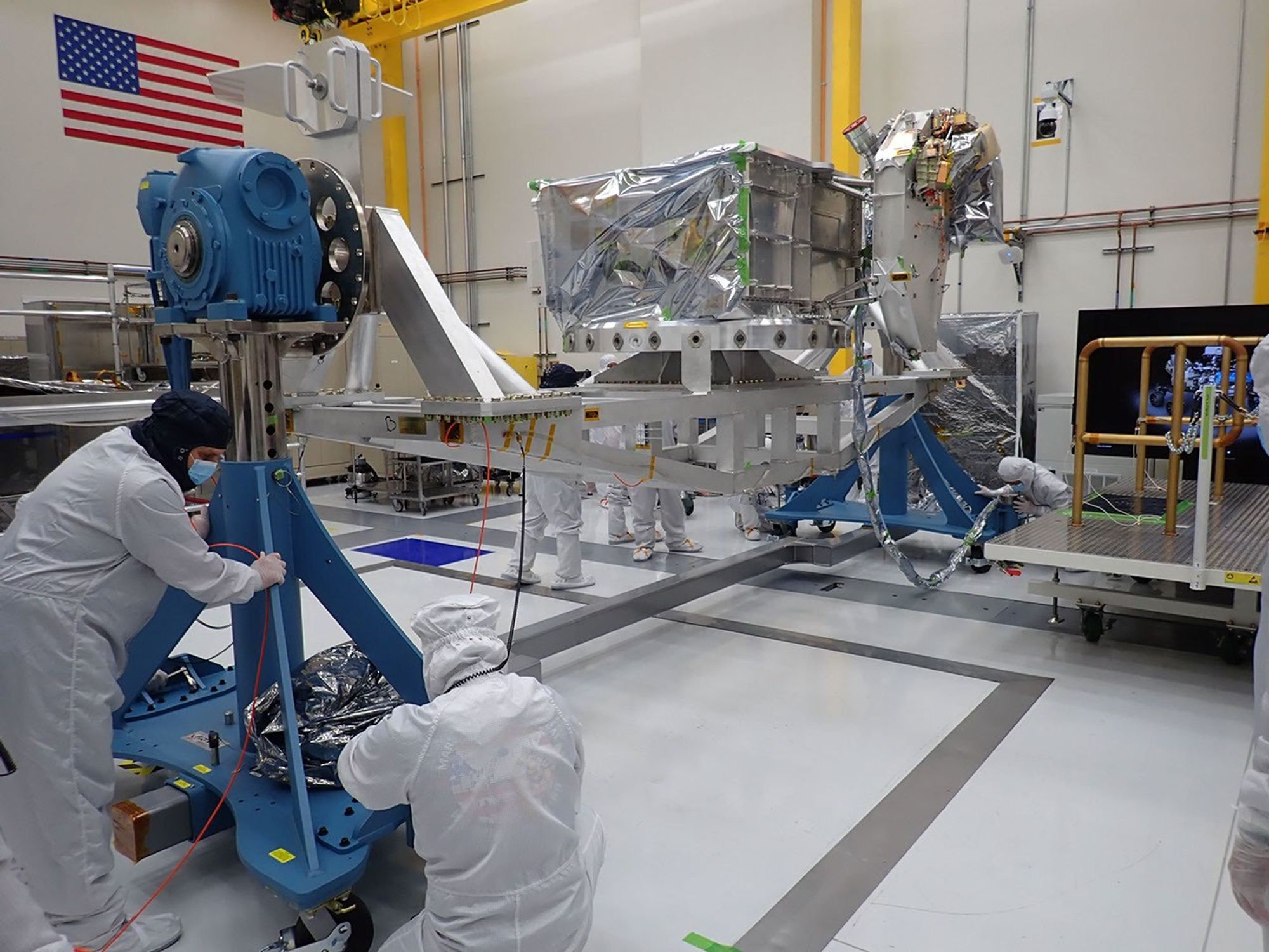 Engineers integrating spacecraft hardware in a cleanroom