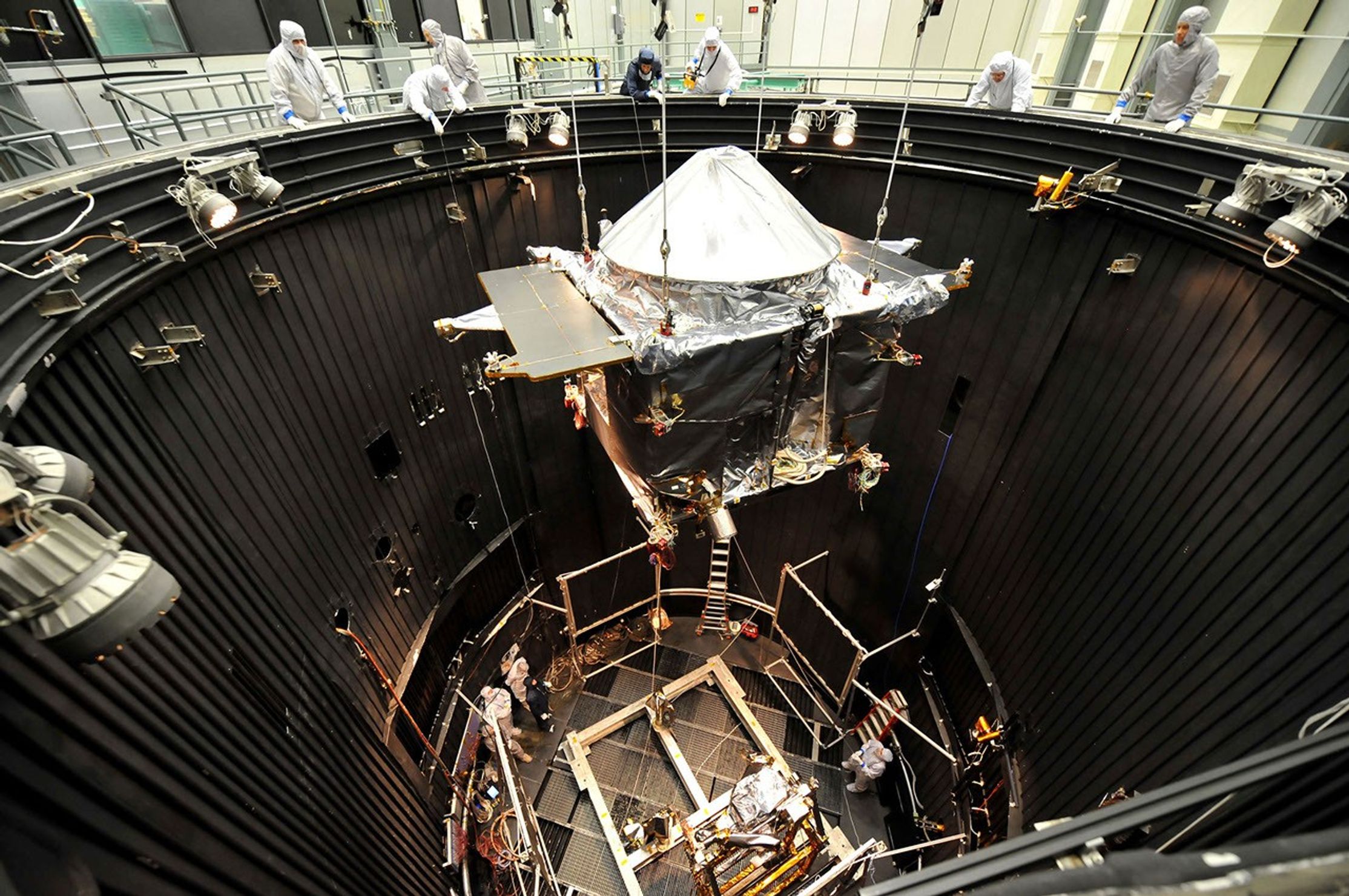 A spacecraft being lowered into a thermal vacuum chamber